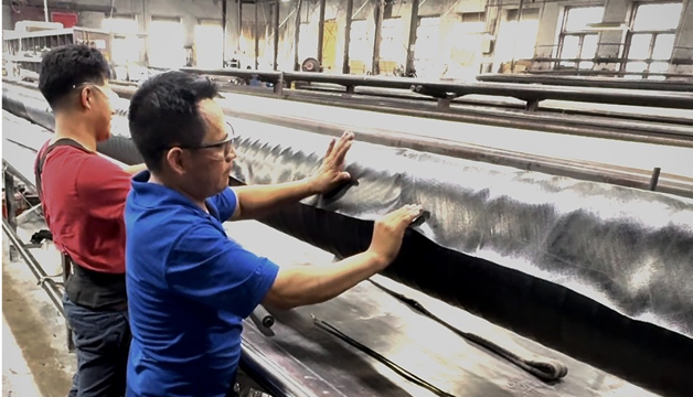 Workers inspecting rubber sheets on a production line